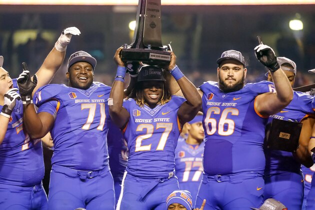 Boise State offensive linesman Rees Odhiambo (71), running back Jay Ajayi (27), and offensive linesman Mario Yakoo (66) hold the trophy after winning the Mountain West Conference championship NCAA college football game against Fresno State in Boise, Idaho, on Saturday, Dec. 6, 2014. Boise State won 28-14. (AP Photo/Otto Kitsinger)