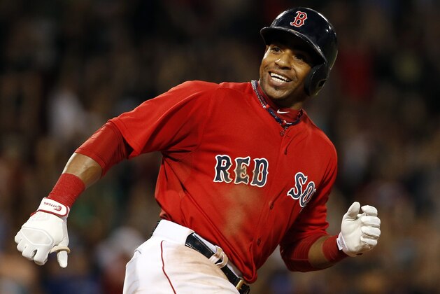 Boston Red Sox's Yoenis Cespedes smiles at teammates charging out of the dugout after hitting the game-winning RBI single against the Toronto Blue Jays during the 10th inning of the Red Sox's 9-8 win in a baseball game at Fenway Park in Boston on Friday, Sept. 5, 2014. (AP Photo/Winslow Townson)