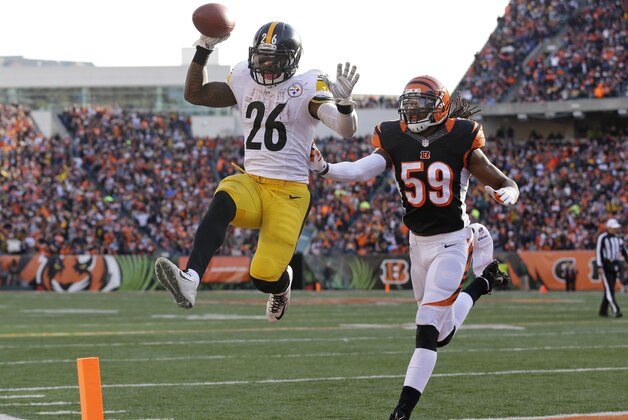 El running back Le'Veon Bell (26) de los Steelers de Pittsburgh anota luego de una recepción de 10 yardas frente a los Bengals de Cincinnati sin que el linebacker Emmanuel Lamur (59) de los Bengals pueda evitarlo, el domingo 7 de diciembre de 2014 en Cincinnati. (Foto AP/Michael Conroy)