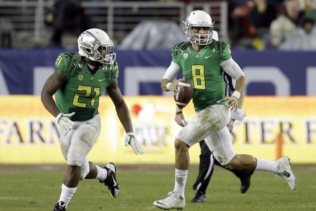 Oregon quarterback Marcus Mariota, right, scrambles out of the pocket behind Royce Freeman (21) during the first half of a Pac-12 Conference championship NCAA college football game against Arizona Friday, Dec. 5, 2014, in Santa Clara, Calif. (AP Photo/Ben Margot)