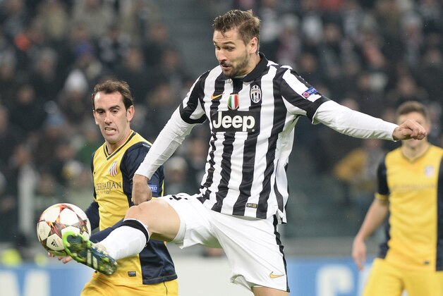 Juventus Fernando Llorente, right, challenges the ball with Atletico Madrid Diego Godin during a Champions League, Group A, soccer match between Juventus and Atletico de Madrid at the Juventus stadium in Turin, Italy, Tuesday, Dec. 9, 2014. (AP Photo/Massimo Pinca)