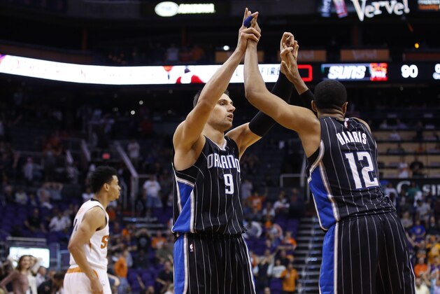 Orlando Magic's Nikola Vucevic (9), of Montenegro, and Tobias Harris (12) celebrate in the closing second of the second half as Phoenix Suns' Gerald Green, left, walks off the court in an NBA basketball game Sunday, Nov. 30, 2014, in Phoenix.  The Magic defeated the Suns 93-90. (AP Photo/Ross D. Franklin)