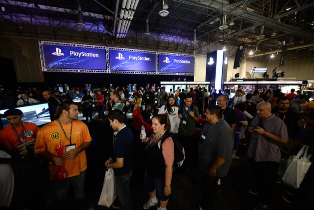 FILE - In this Aug. 28, 2013 file photo, attendees walk near the Sony Playstation booth at the GameStop Expo in Las Vegas. At this week's GameStop Expo, attendees could take titles like