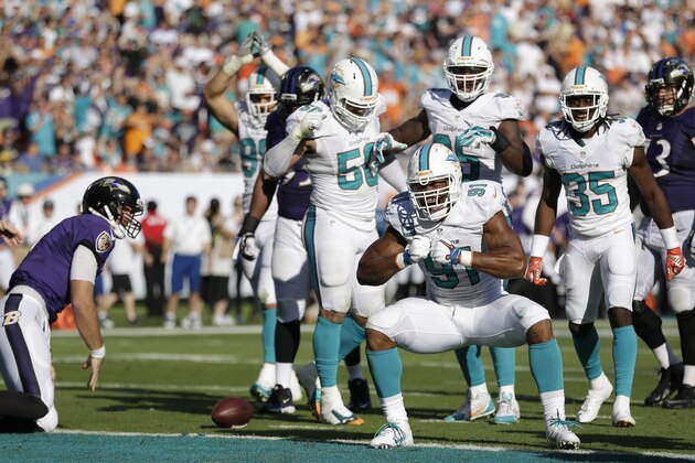 Miami Dolphins defensive end Cameron Wake (91) celebrates after sacking Baltimore Ravens quarterback Joe Flacco, left, during the second half of an NFL football game, Sunday, Dec. 7, 2014, in Miami Gardens, Fla. (AP Photo/Wilfredo Lee)