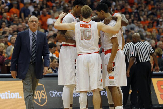 Syracuse head coach Jim Boeheim, left, walks near his players meeting on the court as referees discuss a scuffle that broke out after a flagrant foul one in the second half of an NCAA college basketball game against St. John's in Syracuse, N.Y., Saturday, Dec. 6, 2014. St. John’s won 69-57. (AP Photo/Nick Lisi)