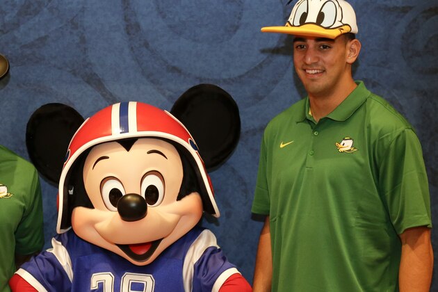 Oregon defensive back Ifo Ekpre-Olomu, left, and Oregon quarterback Marcus Mariota, right, pose for a photo with Mickey Mouse during a media availability prior to the College Football Awards, Wednesday, Dec. 10, 2014, at Disney World in Lake Buena Vista, Fla. The College Football Awards will be held on Thursday evening. (AP Photo/John Raoux)