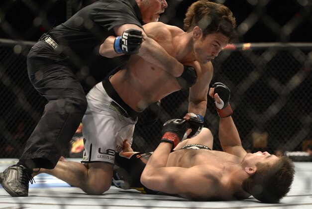 Apr 16, 2014; Quebec City, Quebec, Canada; Sam Stout ( red gloves), London, Ontario, Canada  was defeated by KO/TKO by  KJ Noons (blue gloves) , Kona, HI, USA during their light welterweight bout at Colisee Pepsi. Referee Philippe Chartier stopped the fight. Mandatory Credit: Eric Bolte-USA TODAY Sports