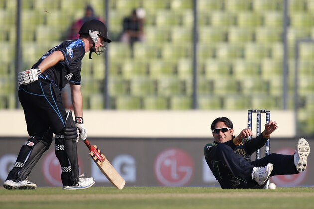 Pakistan's bowler Saeed Ajmal, right, falls on the ground in an unsuccessful attempt to run out New Zealand batsman Colin Munro, left, during their ICC Twenty20 Cricket World Cup warm up match in Dhaka, Bangladesh, Monday, March 17, 2014. (AP Photo/Aijaz Rahi)