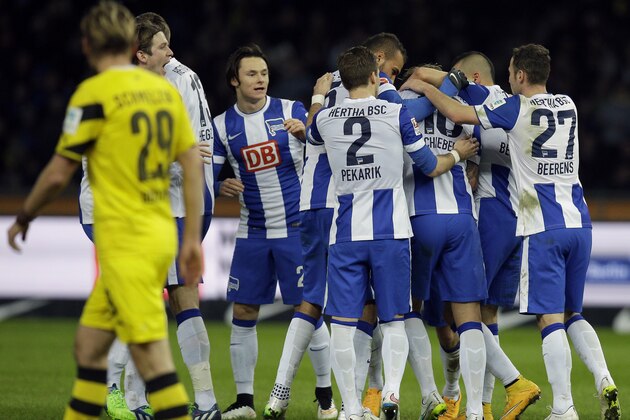 Dortmund's Marcel Schmelzer, front, walks past Berlin's players celebrating their side's first goal scored by Julian Schiebern during the German Bundesliga soccer match between Hertha BSC Berlin and Borussia Dortmund at the Olympia stadium in Berlin, Germany, Saturday, Dec. 13, 2014. (AP Photo/Michael Sohn)