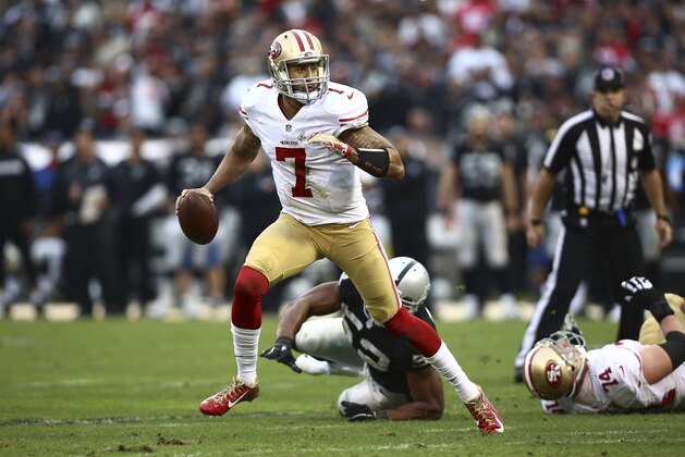 San Francisco 49ers quarterback Colin Kaepernick (7) runs from Oakland Raiders outside linebacker Khalil Mack (52) during the second half of an NFL football game in Oakland, Calif., Sunday, Dec. 7, 2014. (AP Photo/Ryan Kang)