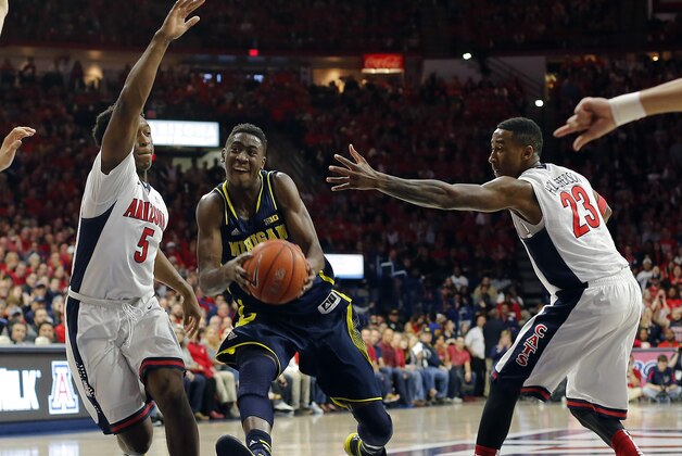 Michigan guard Caris LeVert (23) drives between Arizona forward Stanley Johnson (5) and Rondae Hollis-Jefferson (23) during the first half of an NCAA college basketball game, Saturday, Dec. 13, 2014, in Tucson, Ariz. (AP Photo/Rick Scuteri)