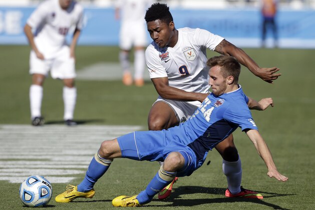 Virginia's Darius Madison (9) and UCLA's Felix Vobejda chase the ball during the first half of an NCAA College Cup championship soccer game in Cary, N.C., Sunday, Dec. 14, 2014. (AP Photo/Gerry Broome)