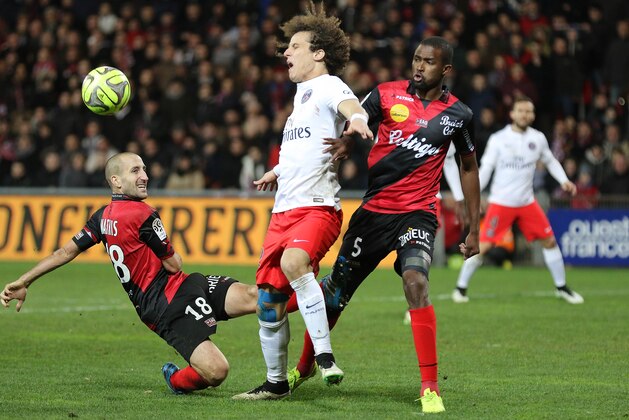 Paris Saint Germain's brazilian defender David Luiz challenges for the ball with Guingamp's french defenders Lionel Mathis, left, and Jeremy Sorbon, right, during their League One soccer match, in Guingamp, western France, Sunday, Dec. 14 , 2014. Guingamp won 1-0. (AP Photo/David Vincent)