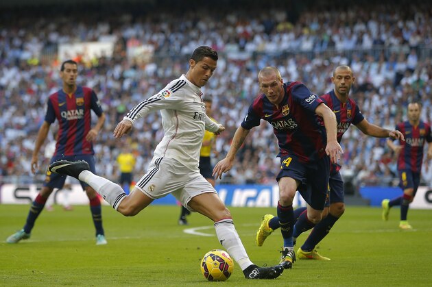 Real Madrid's Cristiano Ronaldo, centre left, in action with Barcelona’s Jeremy Mathieu, centre right, during a Spanish La Liga soccer match between Real Madrid and FC Barcelona at the Santiago Bernabeu stadium in Madrid, Spain, Saturday, Oct. 25, 2014. (AP Photo/Andres Kudacki)