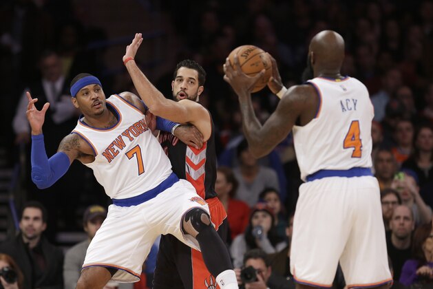 New York Knicks' Carmelo Anthony, left, looks for a pass from Quincy Acy, right, while Toronto Raptors' Landry Fields defends during the first half of an NBA basketball game, Sunday, Dec. 14, 2014 in New York. (AP Photo/Seth Wenig)