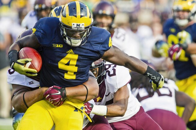 Michigan running back De'Veon Smith (4) tries to break away from Minnesota tackles in the second quarter of an NCAA college football game in Ann Arbor, Mich., Saturday, Sept. 27, 2014. (AP Photo/Tony Ding)
