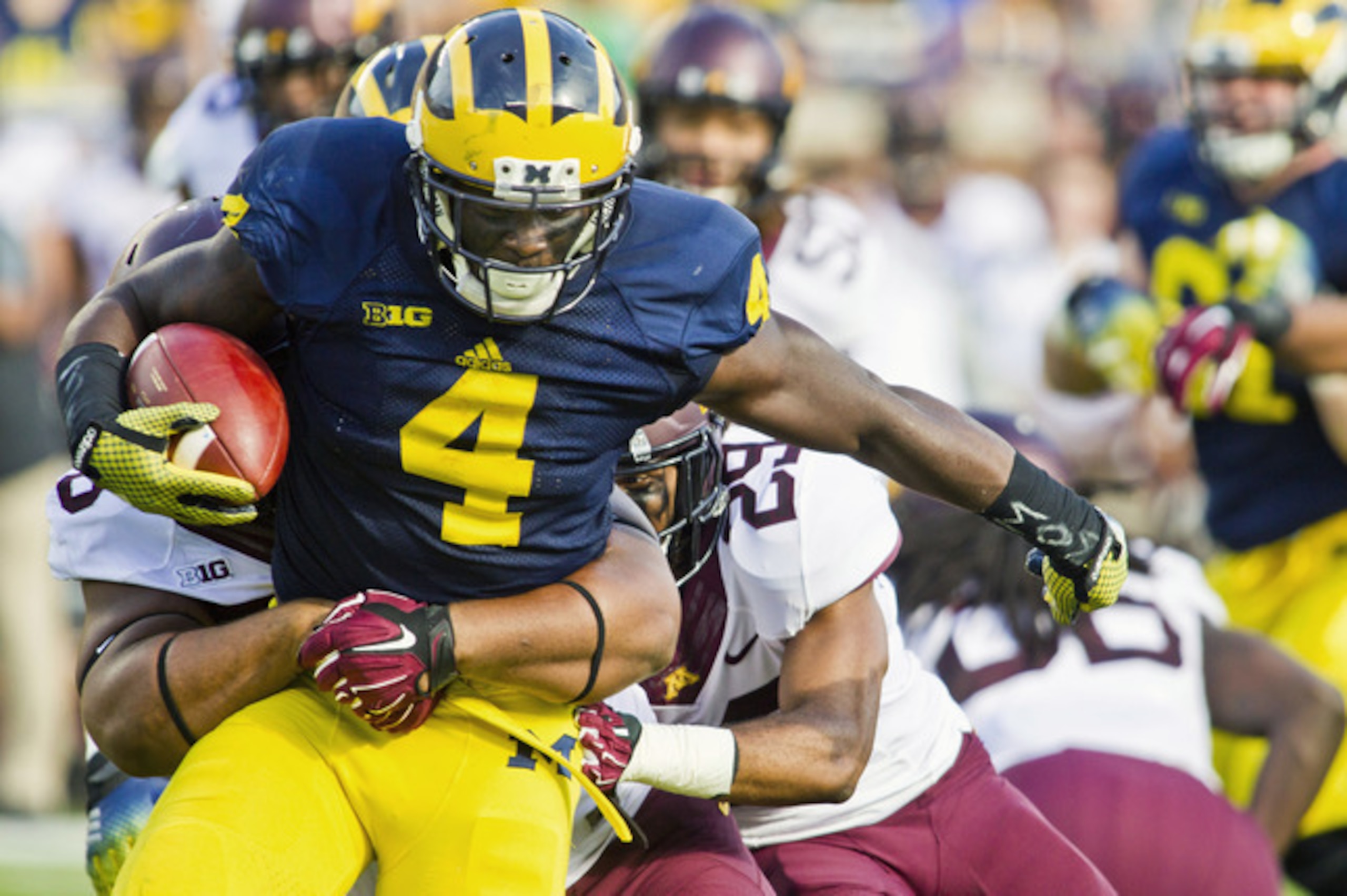 Michigan running back De'Veon Smith (4) tries to break away from Minnesota tackles in the second quarter of an NCAA college football game in Ann Arbor, Mich., Saturday, Sept. 27, 2014. (AP Photo/Tony Ding)