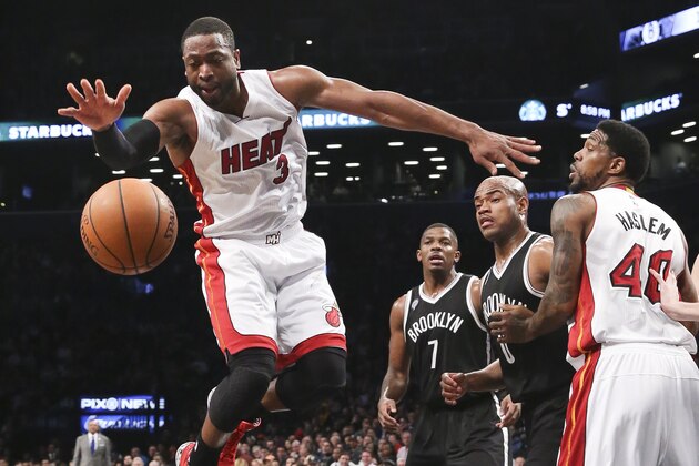 Miami Heat guard Dwyane Wade (3) reaches for a loose ball on a drive as forward Udonis Haslem (40), Brooklyn Nets forward Joe Johnson (7), and guard Jarrett Jack (0) look on in the first half their NBA basketball game at the Barclays Center, Tuesday, Dec. 16, 2014, in New York. (AP Photo/John Minchillo)