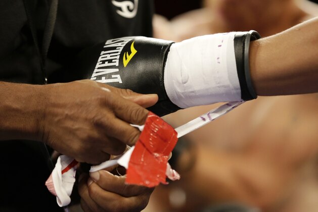 Dennis Galarza has his gloves untaped after he knocked out Cody Walker during a fight, Thursday, July 10, 2014 in Miami. Galarza knocked out Walker at 58 seconds of the first round. (AP Photo/Wilfredo Lee)