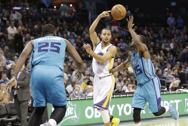 Golden State Warriors' Stephen Curry, center, passes the ball as he is guarded by Charlotte Hornets' Kemba Walker, right, and Al Jefferson, left, during the second half of an NBA basketball game in Charlotte, N.C., Friday, Nov. 28, 2014. The Warriors won 106-101. (AP Photo/Chuck Burton)