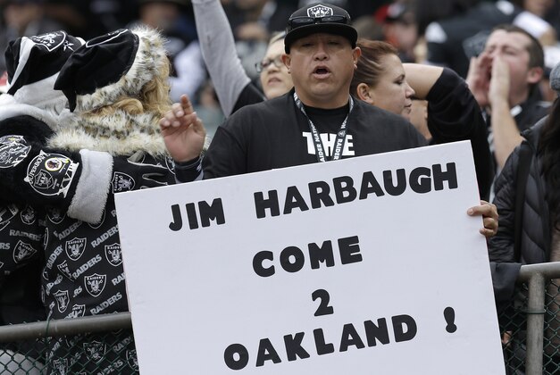 An Oakland Raiders fan holds up a sign for San Francisco 49ers head coach Jim Harbaugh before an NFL football game between the Oakland Raiders and the San Francisco 49ers in Oakland, Calif., Sunday, Dec. 7, 2014. (AP Photo/Ben Margot)