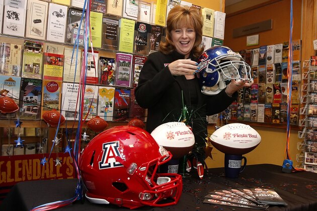 Glendale Convention and Visitors Bureau manager Lorraine Pino laughs as she sets up a Fiesta Bowl display with football helmets of Arizona and Boise State after the teams for the Fiesta Bowl college football game were announced at the Glendale Convention and Visitors Bureau Monday, Dec. 8, 2014, in Glendale, Ariz. (AP Photo/Ross D. Franklin)