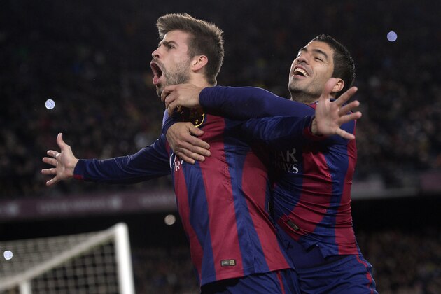 FC Barcelona's Gerard Pique, left, reacts after scoring with his teammate Luis Suarez, from Uruguay, during a Spanish La Liga soccer match against Espanyol at the Camp Nou stadium in Barcelona, Spain, Sunday, Dec. 7, 2014. (AP Photo/Manu Fernandez)