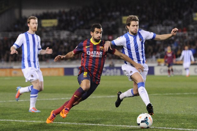 FC Barcelona's Martin Montoya, left, vies for the ball with Real Sociedad's Inigo Martinez, during their Spanish League soccer match, at Anoeta  stadium in San Sebastian, Spain, Saturday, Feb. 22, 2014. (AP Photo/Alvaro Barrientos)