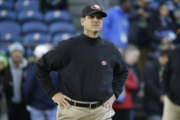 San Francisco 49ers head coach Jim Harbaugh stands on the field before an NFL football game against the Seattle Seahawks, Sunday, Dec. 14, 2014, in Seattle. (AP Photo/Elaine Thompson)
