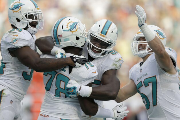 Terrence Fade (78), de los Dolphins de Miami, recibe la congratulación de sus compañeros luego de bloquear un dspeje de los vikiings de Minnesota para el safety que significó el triunfo en el partido del domingo 21 de diciembre de 2014 (AP Foto/Wilfredo Lee)
