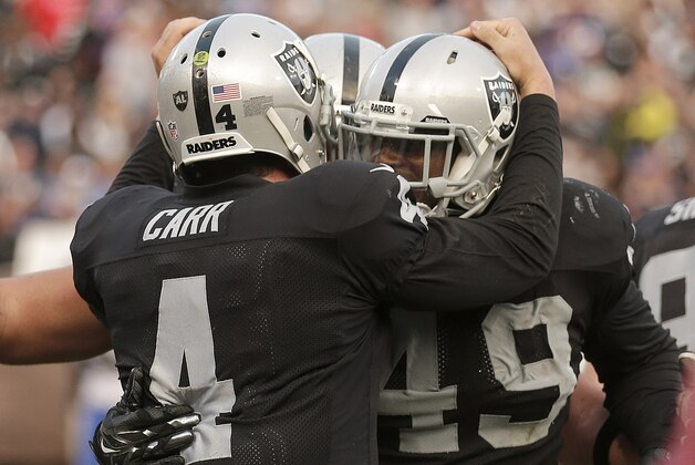 Oakland Raiders running back Jamize Olawale, right, and quarterback Derek Carr (4) celebrate after connecting on a 1-yard touchdown reception against the Buffalo Bills during the fourth quarter of an NFL football game in Oakland, Calif., Sunday, Dec. 21, 2014. (AP Photo/Ben Margot)