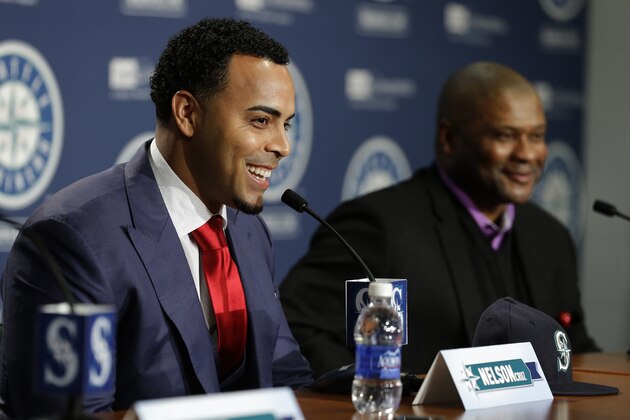 Seattle Mariners Nelson Cruz, left, smiles as he talks to reporters while sitting next to manager Lloyd McClendon, right, after Cruz was introduced during a baseball news conference, Thursday, Dec. 4, 2014, in Seattle. (AP Photo/Ted S. Warren)