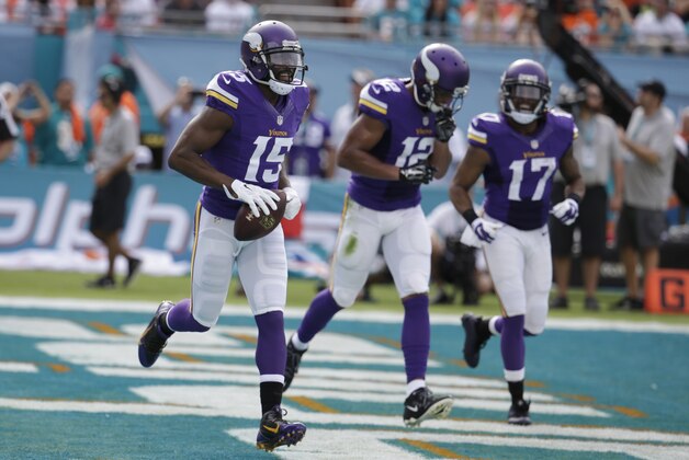 Minnesota Vikings wide receiver Greg Jennings (15) runs with the ball after scoring a touchdown during the first half of an NFL football game against the Miami Dolphins, Sunday, Dec. 21, 2014, in Miami Gardens, Fla. To the right are Minnesota Vikings wide receiver Charles Johnson (12) and Minnesota Vikings wide receiver Jarius Wright (17). (AP Photo/Lynne Sladky)