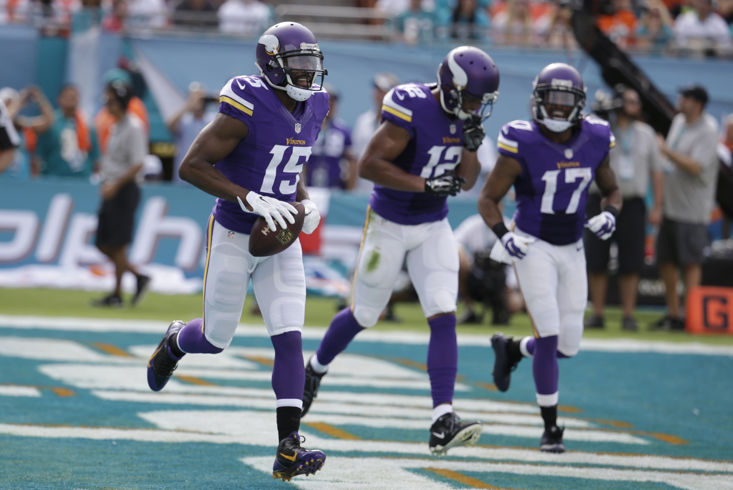 Minnesota Vikings wide receiver Greg Jennings (15) runs with the ball after scoring a touchdown during the first half of an NFL football game against the Miami Dolphins, Sunday, Dec. 21, 2014, in Miami Gardens, Fla. To the right are Minnesota Vikings wide receiver Charles Johnson (12) and Minnesota Vikings wide receiver Jarius Wright (17). (AP Photo/Lynne Sladky)