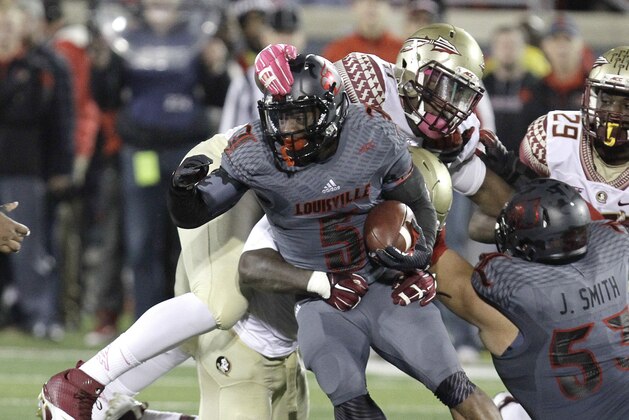 Louisville's Michael Dyer, center, is wrapped up by Florida State's Reggie Northrup, and Derrick Mitchell Jr., rear, during the second half of their NCAA college football game in Louisville, Ky., Thursday, Oct. 30, 2014.  Florida State defeated Louisville 42 - 31. (AP Photo/Garry Jones)