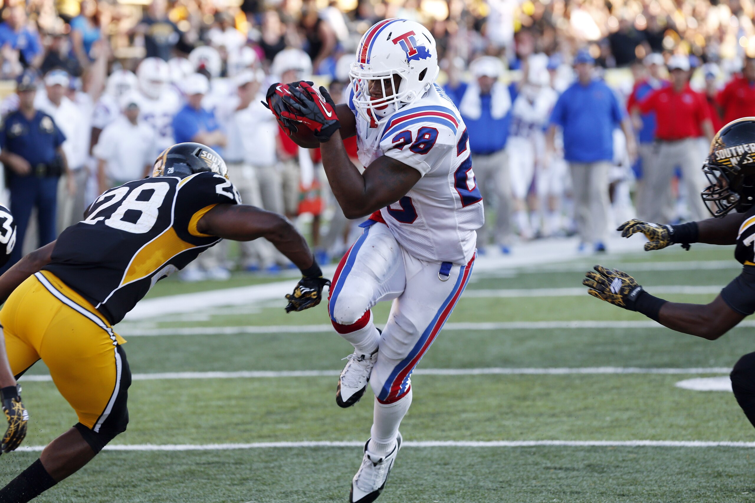 Louisiana Tech running back Kenneth Dixon (28) dives past Southern Mississippi defensive backs Jacorius Cotton (28) and Jomez Applewhite (7) for a touchdown during the second half of an NCAA college football game in Hattiesburg, Miss., Saturday, Oct. 25, 2014. (AP Photo/Rogelio V. Solis)