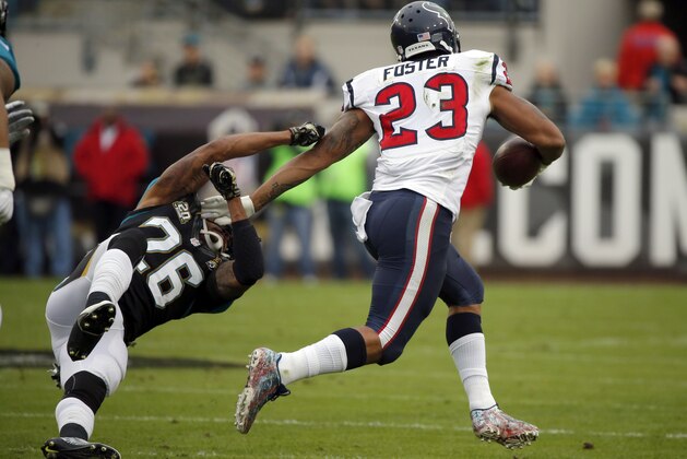 Houston Texans running back Arian Foster (23) stiff arms Jacksonville Jaguars free safety Josh Evans (26) as he runs for yardage during the first half of an NFL football game, Sunday, Dec. 7, 2014, in Jacksonville, Fla. (AP Photo/Stephen B. Morton)