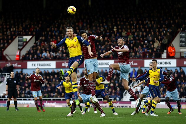 LONDON, ENGLAND - DECEMBER 28:  Per Mertesacker of Arsenal jumps for the ball with James Tomkins of West Ham during the Barclays Premier League match between West Ham United and Arsenal at Boleyn Ground on December 28, 2014 in London, England.  (Photo by Steve Bardens/Getty Images)