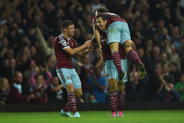 West Ham United’s Stewart Downing, centre, celebrates setting up his team's third goal, with West Ham United’s Aaron Cresswell, left, and West Ham United’s Mark Noble, right, during their English Premier League soccer match against Liverpool at Upton Park, London, Saturday, Sept. 20, 2014. (AP Photo/Tim Ireland)