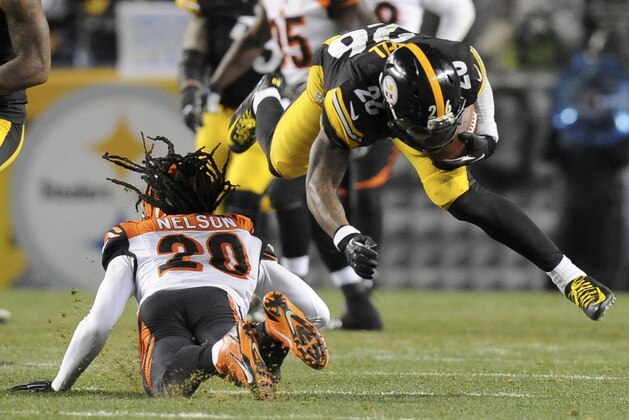 El running back de los Steelers de Pittsburgh Le'Veon Bell (26) recibe un golpe en la rodilla del safety de los Bengals Reggie Nelson (20) que le causó una lesión que pone en duda su participación en el próximo partido de su escuadra. (Foto AP/Don Wright)