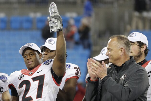 Georgia's Nick Chubb, left, holds up the game MVP trophy as coach Mark Richt, right, applauds after the Belk Bowl NCAA college football game in Charlotte, N.C., Tuesday, Dec. 30, 2014. Georgia defeated Louisville 37-14. (AP Photo/Chuck Burton)