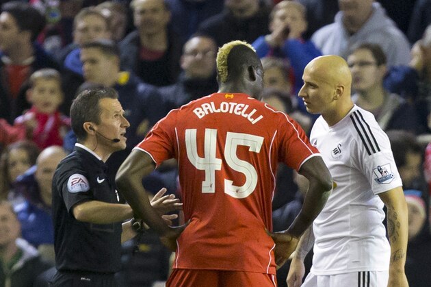 Liverpool's Mario Balotelli, centre, and Swansea's Jonjo Shelvey are spoken to by referee Keith Stroud, during the English League Cup soccer match between Liverpool and Swansea at Anfield Stadium, Liverpool, England, Tuesday Oct. 28, 2014. (AP Photo/Jon Super)