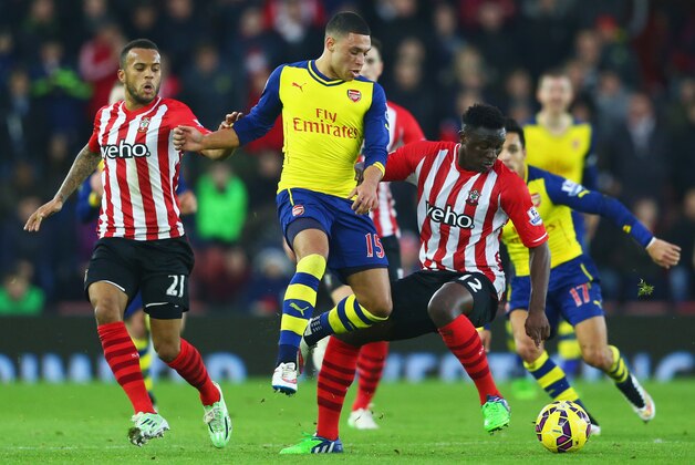 SOUTHAMPTON, ENGLAND - JANUARY 01:  Alex Oxlade-Chamberlain of Arsenal takes on Victor Wanyama (R) and Ryan Bertrand of Southampton (L) during the Barclays Premier League match between Southampton and Arsenal at St Mary's Stadium on January 1, 2015 in Southampton, England.  (Photo by Michael Steele/Getty Images)