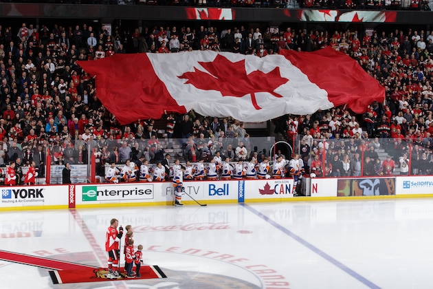 OTTAWA, ON - DECEMBER 4: Daniel Alfredsson #11 of the Ottawa Senators and his family stand at centre ice as a Canadian flag gets passed in the crowd prior to a ceremonial puck drop in his honor during an NHL game against the New York Islanders at Canadian Tire Centre on December 4, 2014 in Ottawa, Ontario, Canada.  (Photo by Jana Chytilova/Freestyle Photography/Getty Images)