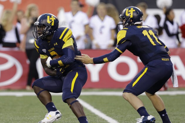 Toledo quarterback Logan Woodside (11) hands off to running back Kareem Hunt (3) in the first half of an NCAA college football game against Cincinnati, Friday, Sept. 12, 2014, in Cincinnati. (AP Photo/Al Behrman)