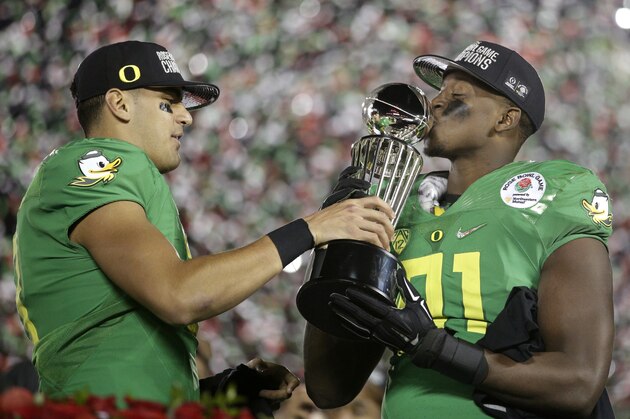 Oregon quarterback Marcus Mariota, left, and linebacker Tony Washington celebrate with the trophy after a 59-20 win over Florida State during the second half of the Rose Bowl NCAA college football playoff semifinal, Thursday, Jan. 1, 2015, in Pasadena, Calif.  (AP Photo/Jae C. Hong)