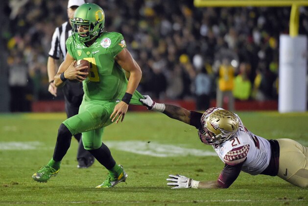Oregon quarterback Marcus Mariota scores past Florida State defensive end Chris Casher during the second half of the Rose Bowl NCAA college football playoff semifinal, Thursday, Jan. 1, 2015 in Pasadena, Calif. (AP Photo/Mark J. Terrill)