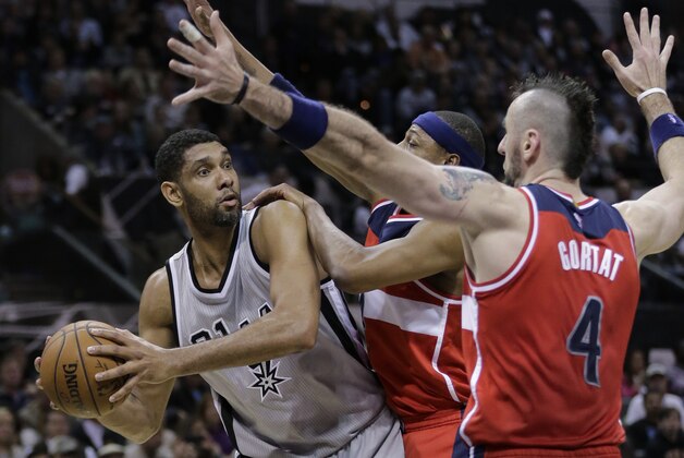 San Antonio Spurs' Tim Duncan, left, is pressured by Washington Wizards' Paul Pierce, center, and Marcin Gortat (4) during the second half of an NBA basketball game, Saturday, Jan. 3, 2015, in San Antonio. (AP Photo/Eric Gay)