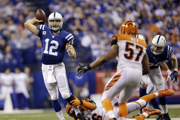 El quarterback Andrew Luck (12) de los Colts de Indianápolis lanza un pase de 36 yardas mientras trata de zafarse de la tacleada de Carlos Dunlap (96) de los Bengals de Cincinnati, el domingo 4 de enero de 2015. (AP Foto/AJ Mast)