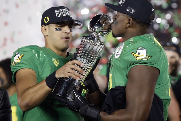 Oregon quarterback Marcus Mariota, left, and linebacker Tony Washington celebrate with the trophy after their win against Florida State during the second half of the Rose Bowl NCAA college football playoff semifinal, Thursday, Jan. 1, 2015, in Pasadena, Calif. (AP Photo/Lenny Ignelzi)